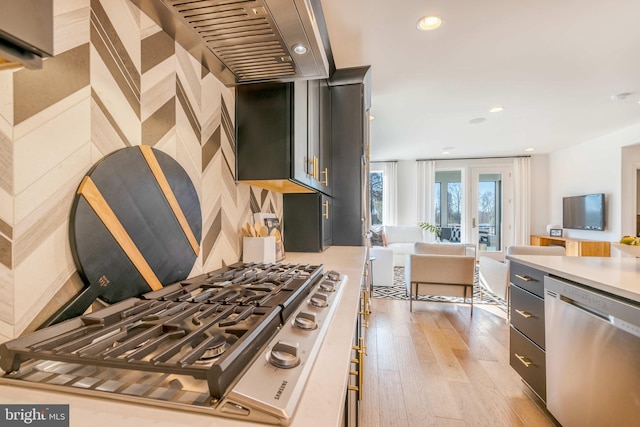 kitchen featuring appliances with stainless steel finishes, light wood-type flooring, french doors, and exhaust hood