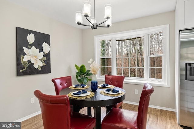 dining area with light wood-type flooring and a notable chandelier