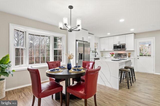 dining area featuring light hardwood / wood-style floors, sink, and an inviting chandelier