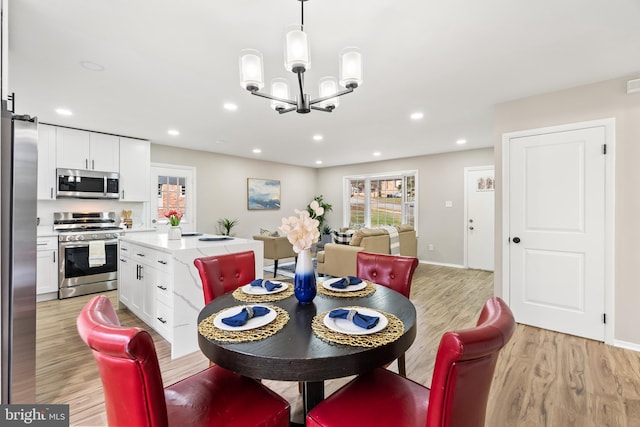 dining room with light wood-type flooring and an inviting chandelier