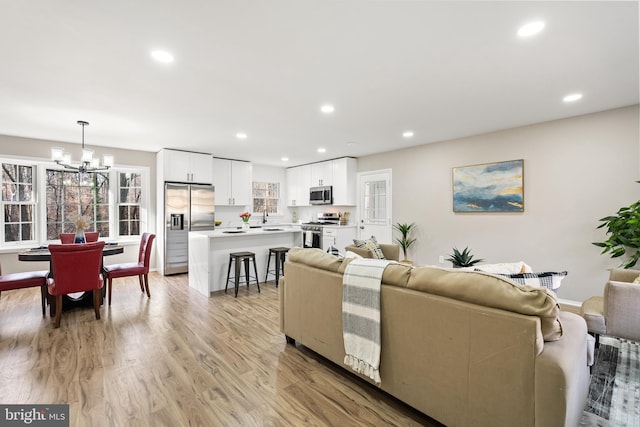 living room featuring sink, an inviting chandelier, and light wood-type flooring