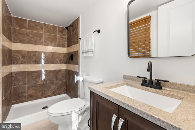 bathroom featuring tile patterned flooring, vanity, toilet, and a tile shower