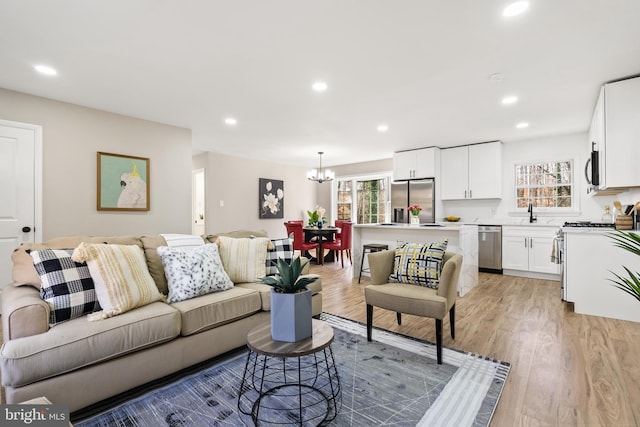 living room featuring a wealth of natural light, light hardwood / wood-style flooring, a chandelier, and sink