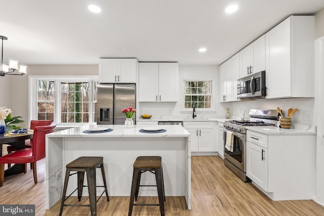 kitchen featuring a center island, white cabinets, stainless steel appliances, and decorative light fixtures