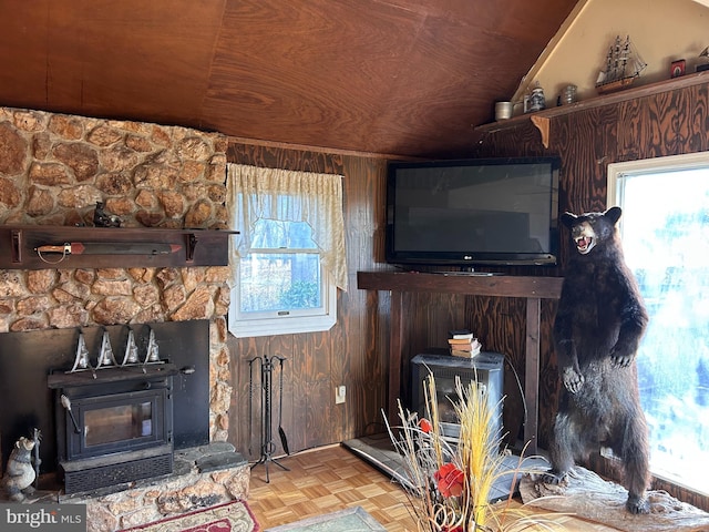 living room featuring a wood stove, wood walls, wood ceiling, and vaulted ceiling