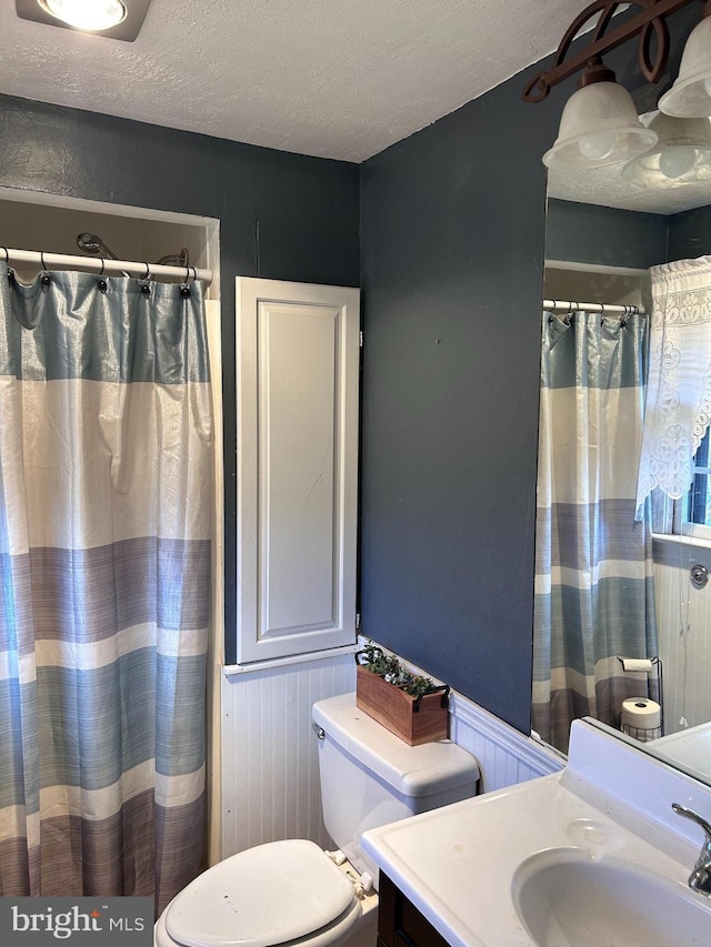 bathroom featuring vanity, a textured ceiling, toilet, and wood walls