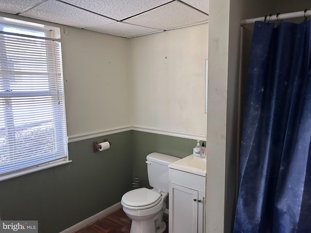 bathroom featuring hardwood / wood-style floors, a drop ceiling, toilet, and vanity