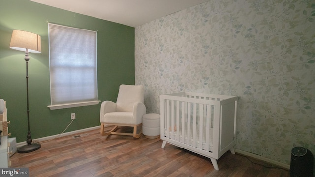 bedroom featuring a crib and hardwood / wood-style flooring