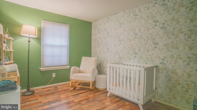 bedroom featuring hardwood / wood-style floors and a nursery area