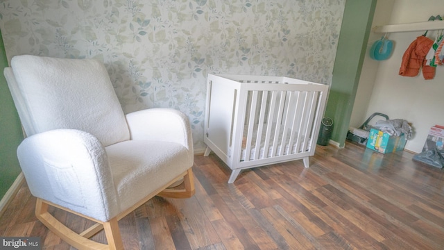 bedroom featuring dark hardwood / wood-style flooring, a crib, and radiator