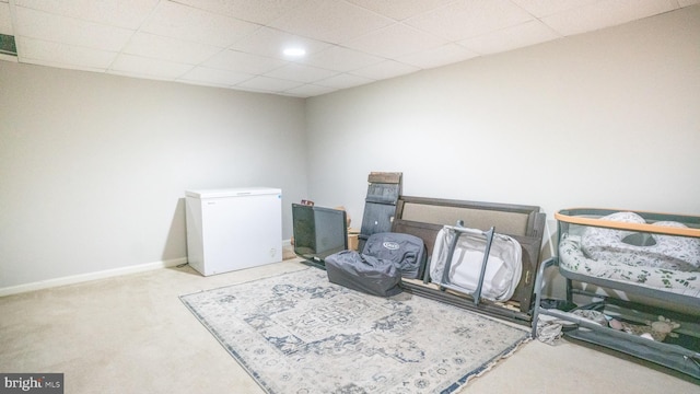 living area featuring light carpet and a drop ceiling