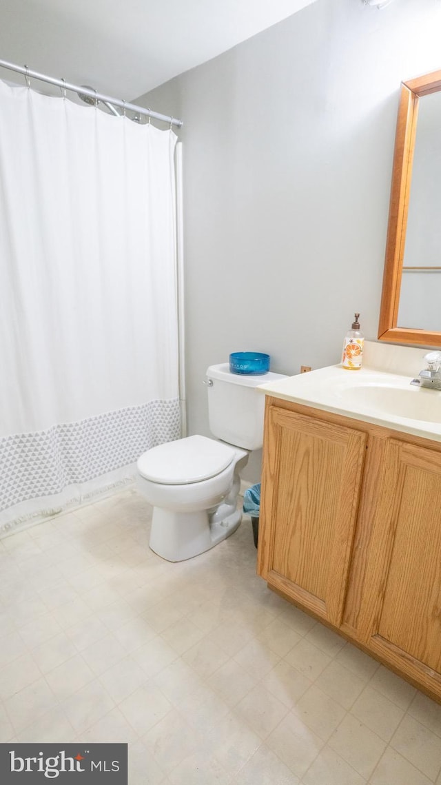 bathroom featuring curtained shower, vanity, and toilet