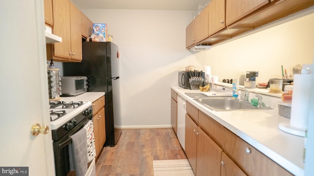 kitchen with light wood-type flooring, sink, and gas range gas stove