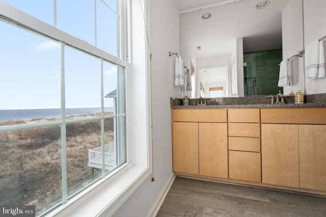 bathroom featuring vanity, an enclosed shower, wood-type flooring, and a water view