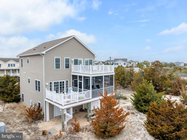 rear view of house with a balcony, a sunroom, and a wooden deck