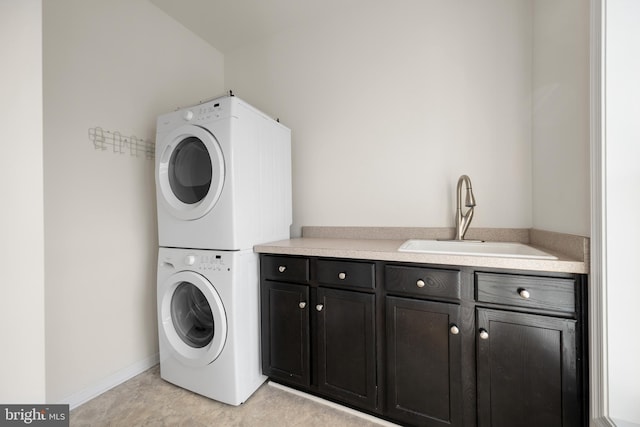 laundry area with cabinets, stacked washer and dryer, and sink