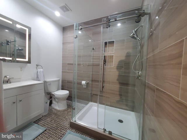 bathroom featuring toilet, a shower with door, and vanity