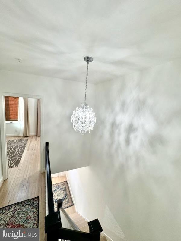 staircase with hardwood / wood-style floors and a notable chandelier