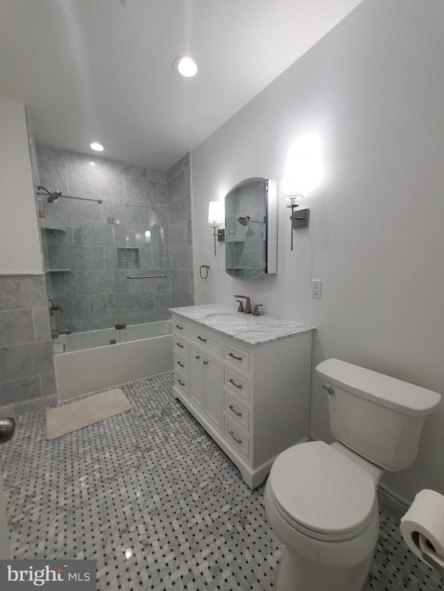 full bathroom featuring vanity, combined bath / shower with glass door, and toilet