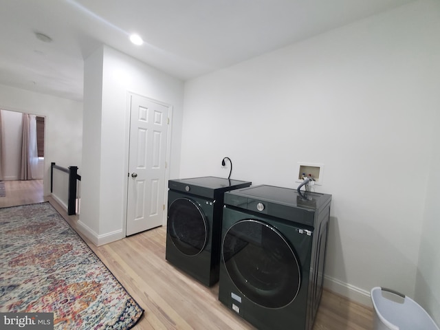 laundry room with independent washer and dryer and light hardwood / wood-style flooring