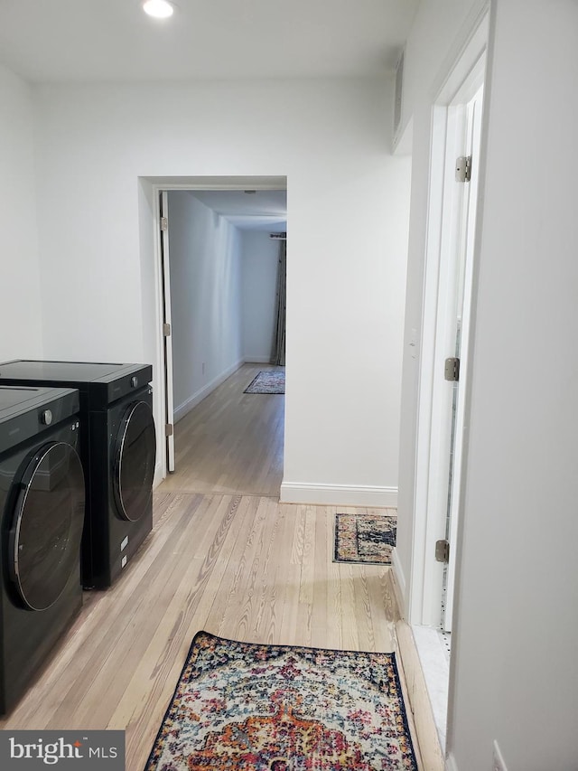 laundry room featuring separate washer and dryer and light hardwood / wood-style flooring