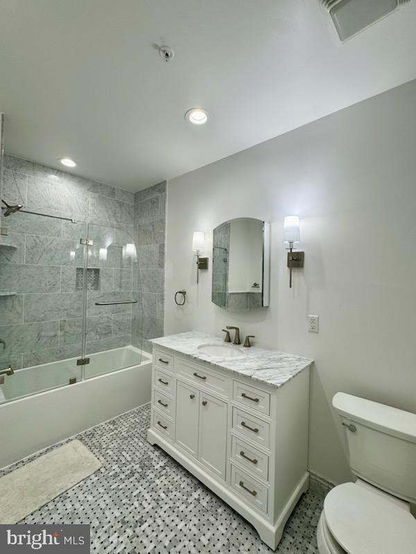 full bathroom with tile patterned flooring, bath / shower combo with glass door, vanity, and toilet