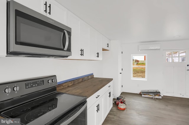 kitchen with a wall unit AC, butcher block counters, white cabinets, and black range with electric cooktop