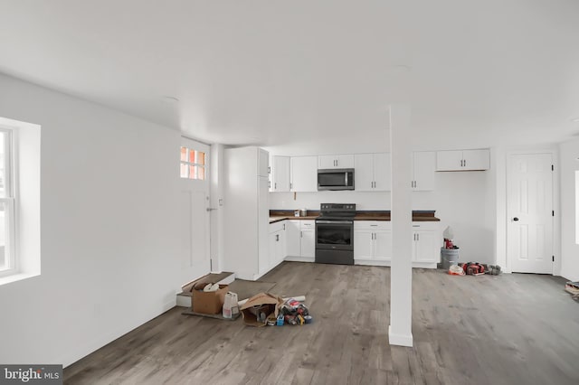 kitchen with white cabinets, light hardwood / wood-style floors, and black / electric stove