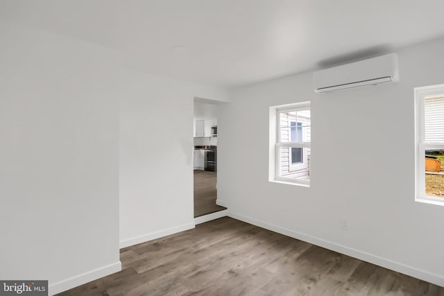 unfurnished room featuring hardwood / wood-style flooring and an AC wall unit