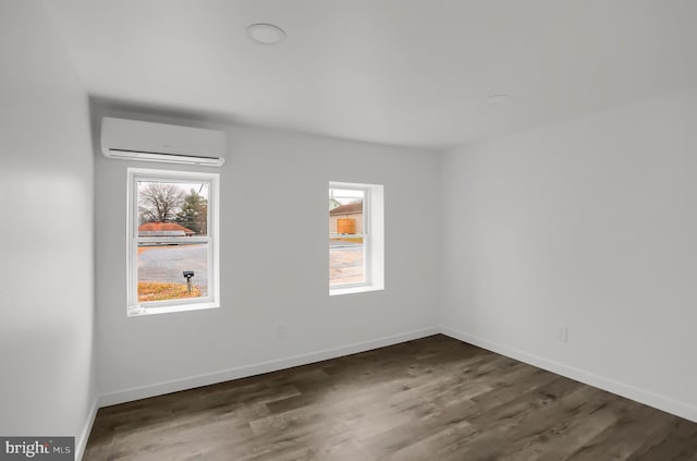 unfurnished room featuring a wall unit AC and dark hardwood / wood-style flooring