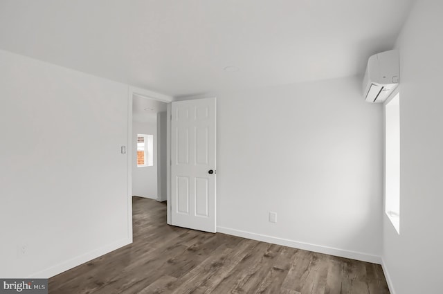 unfurnished room featuring an AC wall unit and dark hardwood / wood-style flooring