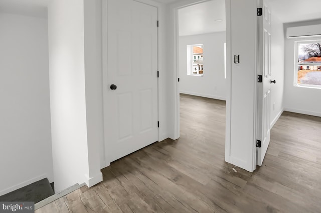 corridor featuring light hardwood / wood-style floors and an AC wall unit