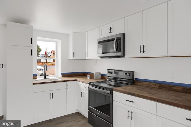 kitchen with dark hardwood / wood-style flooring, white cabinets, sink, black electric range, and butcher block counters