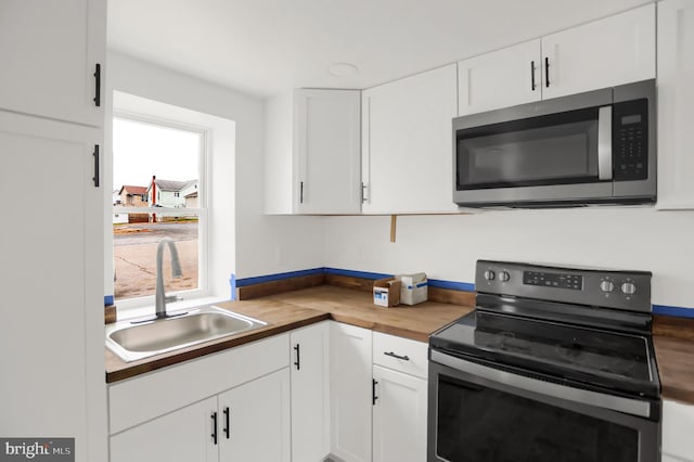 kitchen with white cabinetry, black range with electric stovetop, sink, and wooden counters