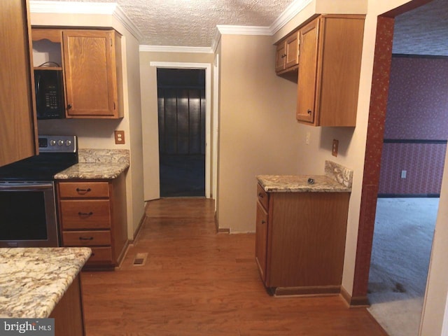 kitchen with electric range, light stone counters, wood-type flooring, a textured ceiling, and ornamental molding