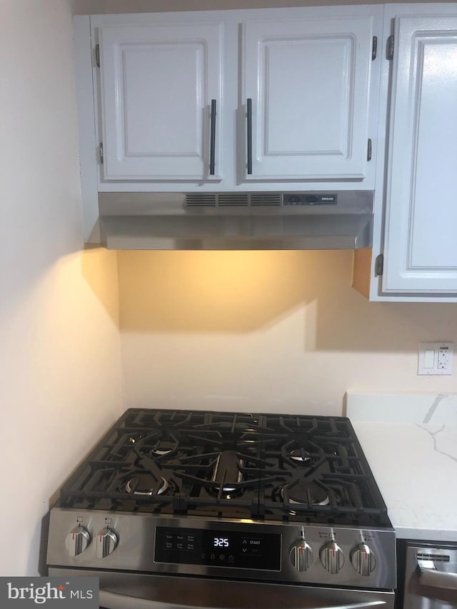 kitchen featuring stainless steel range, white cabinets, and light stone countertops