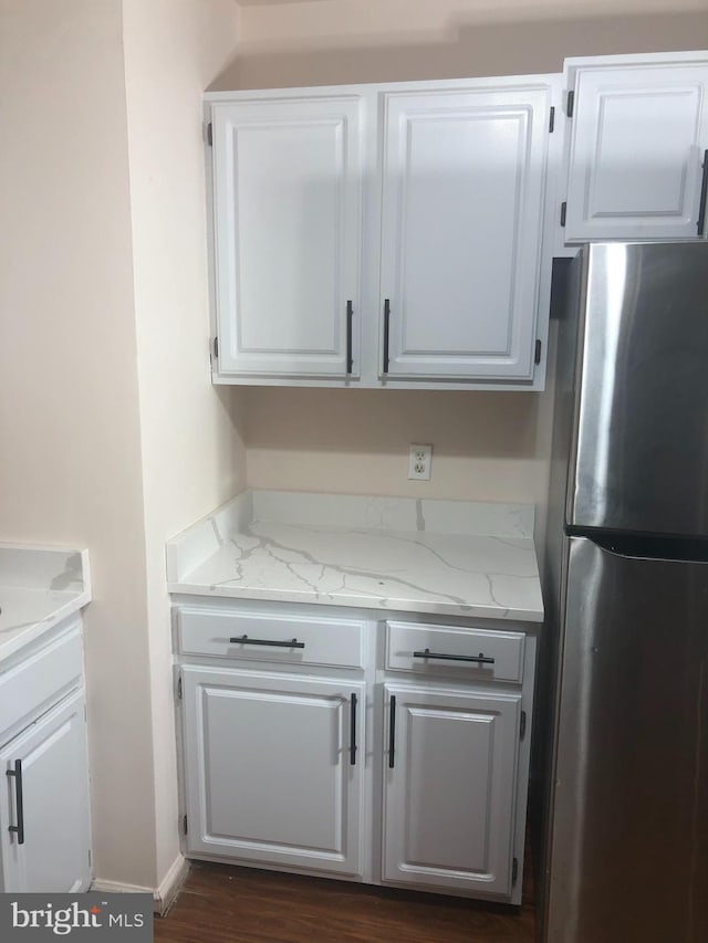 kitchen featuring light stone counters, white cabinetry, and stainless steel refrigerator