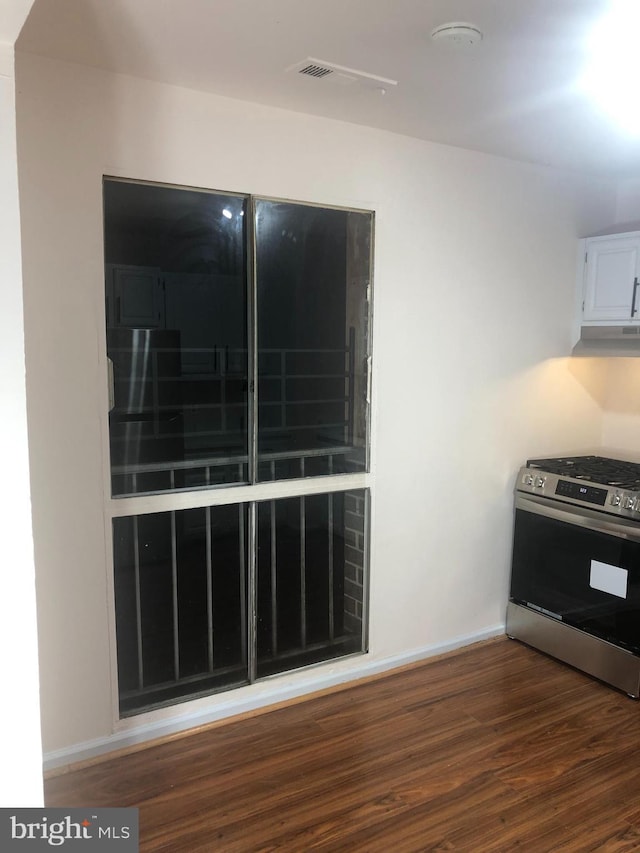 kitchen with dark hardwood / wood-style floors, white cabinetry, and stainless steel stove