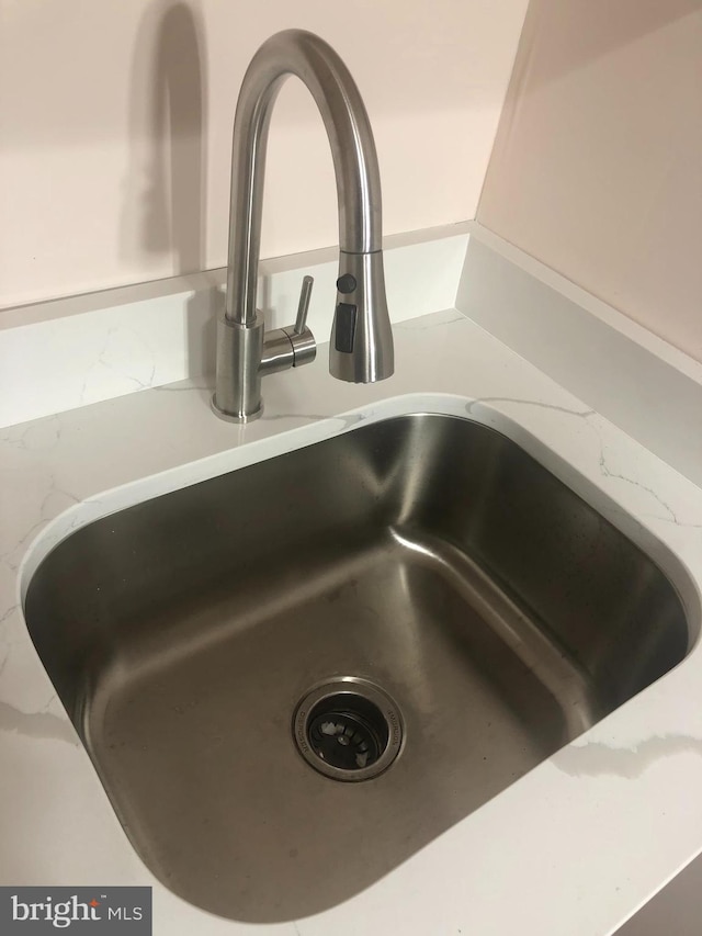 room details featuring light stone countertops and sink