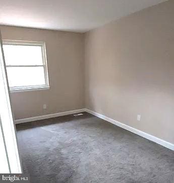 spare room featuring dark carpet