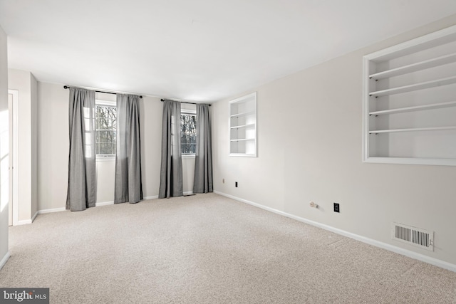 carpeted spare room with built in shelves