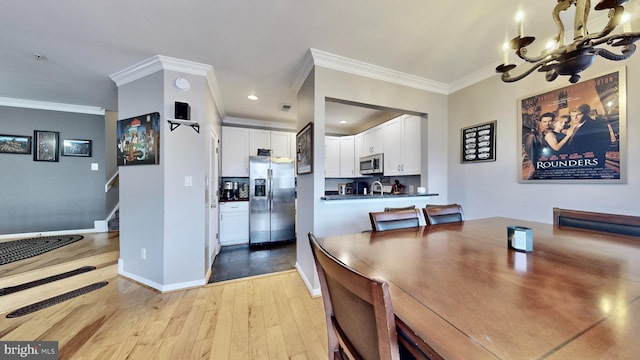 dining room featuring light hardwood / wood-style flooring, an inviting chandelier, and crown molding