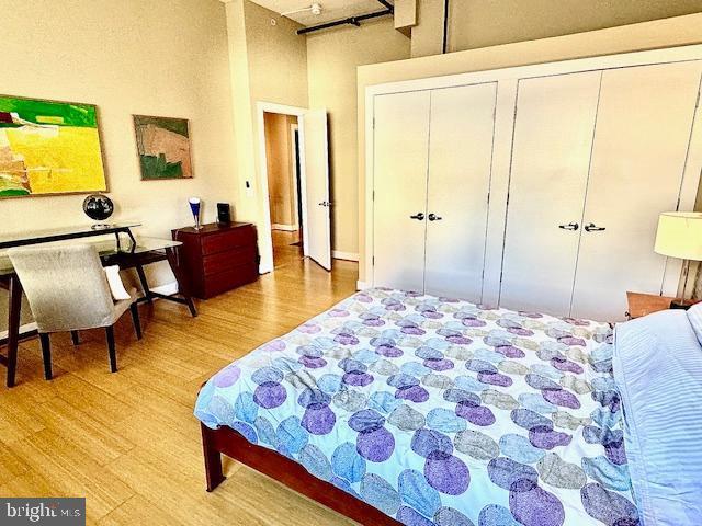 bedroom featuring a high ceiling, light hardwood / wood-style floors, and two closets