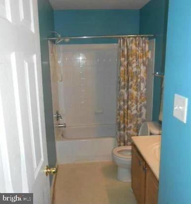 full bathroom featuring shower / bath combination with curtain, vanity, and toilet