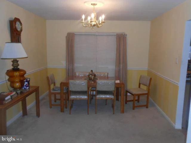 carpeted dining space featuring an inviting chandelier