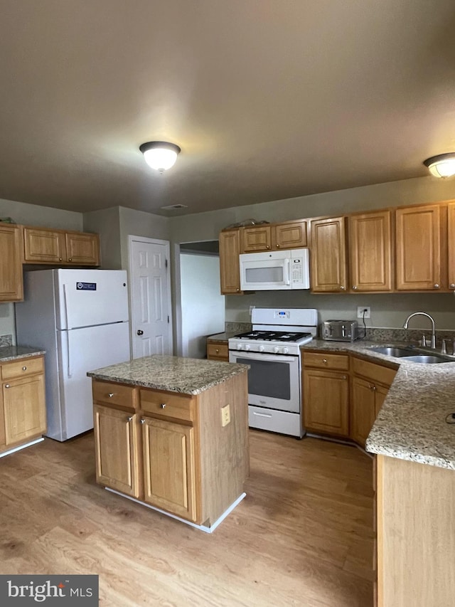 kitchen with light hardwood / wood-style floors, a center island, white appliances, and sink