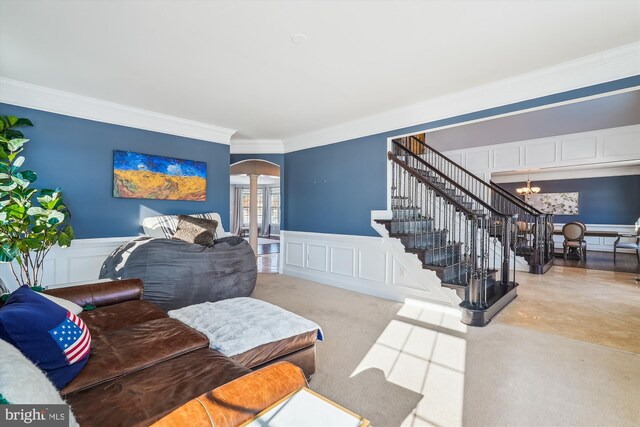 living room featuring light carpet, crown molding, a chandelier, and ornate columns