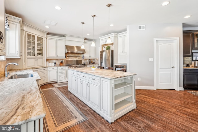 kitchen featuring appliances with stainless steel finishes, hanging light fixtures, decorative backsplash, a kitchen island, and sink