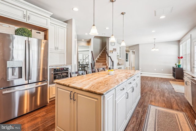 kitchen with stainless steel appliances, white cabinetry, a kitchen island, and hanging light fixtures