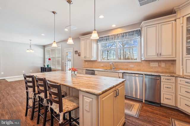 kitchen with dishwasher, hanging light fixtures, decorative backsplash, a kitchen island, and cream cabinetry